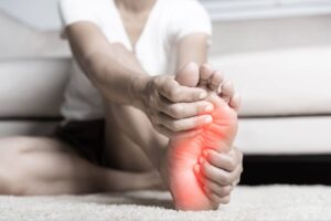 Person holding foot as they experience diabetic neuropathy.